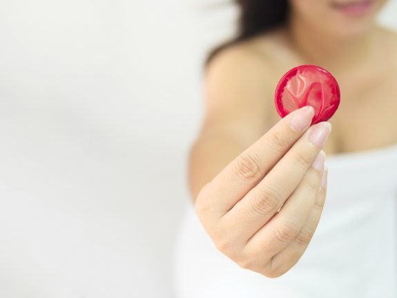 lady is giving red condom safe sex contraception concept - Alagoas tem o menor número de casos de Sífilis do Nordeste