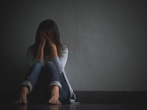 sad woman hug her knee cry sitting alone empty room - Mulheres jovens apresentam mais queixas de sofrimento mental durante a pandemia